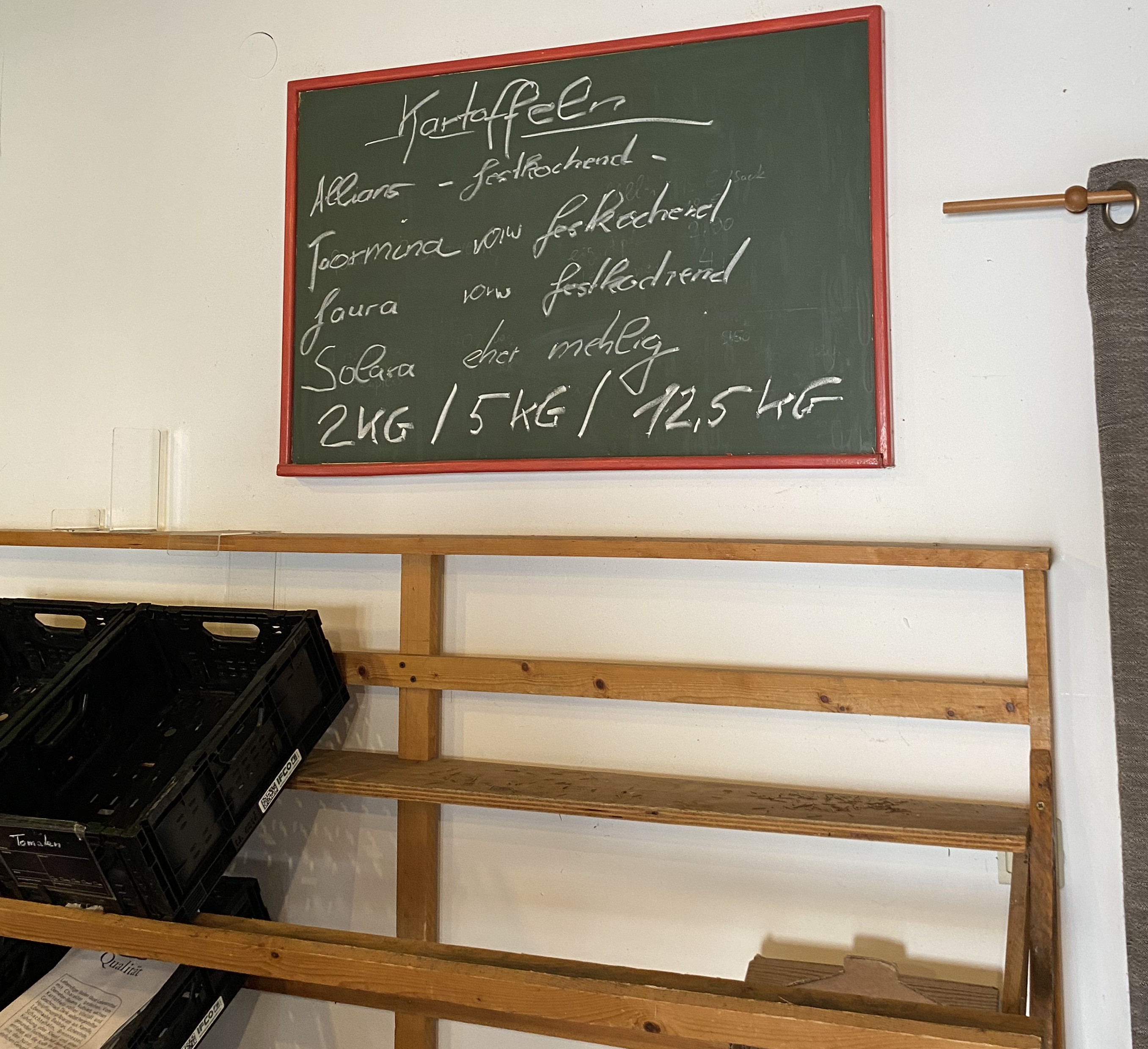 Der Verkaufsbereich der Kartoffeln im Hofladen. An der Wand sieht man ein Schild, das alle Kartoffelsorten aufführt