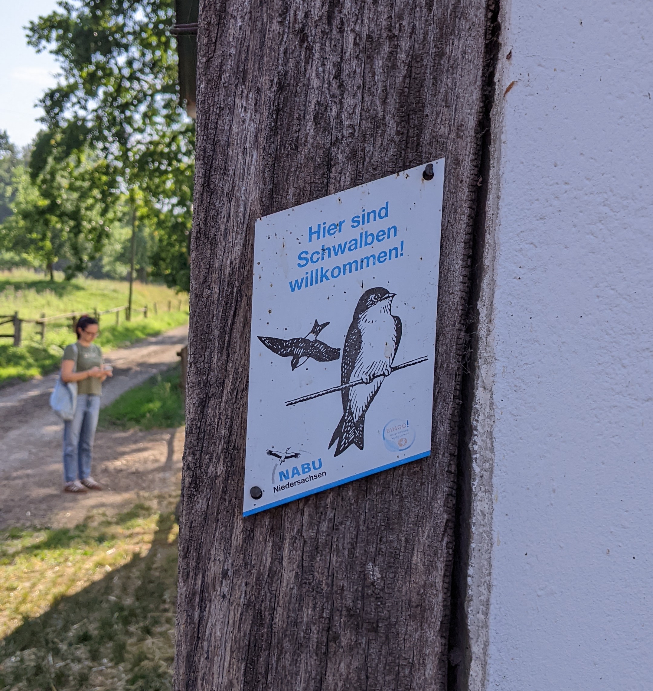 Am Gebäude hängt ein Schild vom NABU mit der Aufschrift “Hier sind Schwalben willkommen”